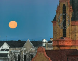 A near-full moon sets with a view of the Anderson County Courthouse, 11 hours before the official rising of the Full Wolf Moon around 6 p.m., light begins to shine for the day as the morning breaks though in Anderson, S.C. Friday, January 6, 2023.